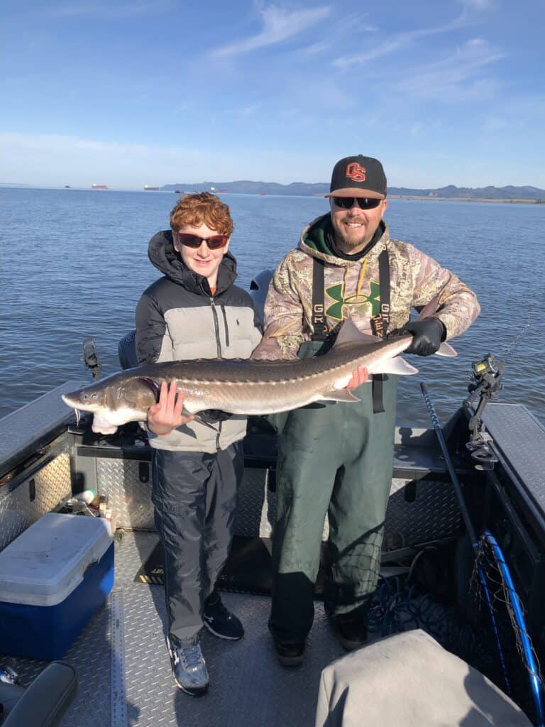 Clients holding a nice keeper sturgeon on the Columbia River in Astoria